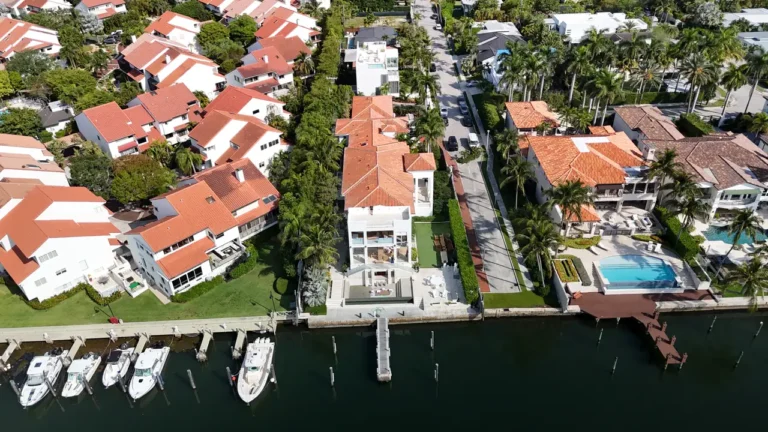 High-altitude drone view of the expansive clay tile roof and surrounding lush landscaping of the Coconut Grove property.